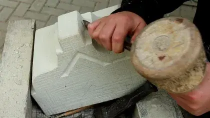 Hand hält Holzhammer und fügt Stein ein