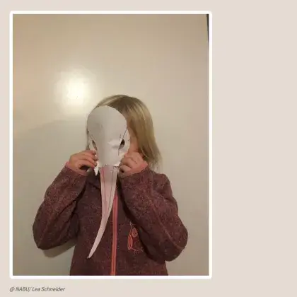 Kind mit Storchenmaske